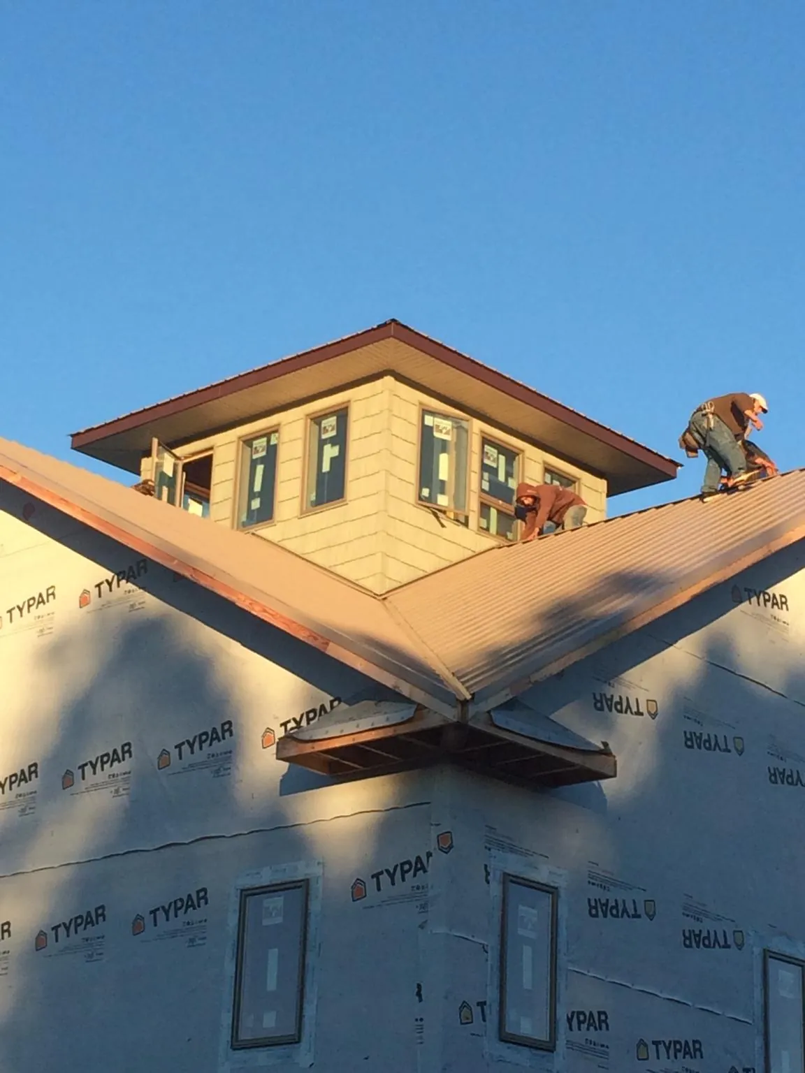 Roofers working around a rooftop cupola on a new metal roof at sunset — Roof Waterproofing in Lawndale by Roofing Brothers